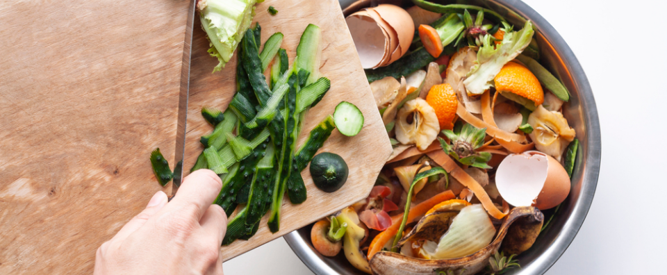 Vegetable peels are thrown from cutting board into an iron bowl with organic food waste. Food leftovers ready to compost. Environmentally responsible behavior, ecological, recycling waste concept.